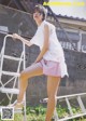 A woman in a white shirt and pink skirt posing on a ladder.