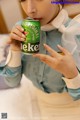 A woman in a blue shirt is holding a can of beer.