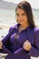 A woman in a purple shirt posing on the beach.