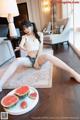 A woman sitting on the floor next to a plate of watermelon.