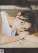 A woman laying on top of a table with her hand on her chin.