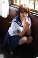 A woman in a school uniform sitting on a window sill.