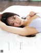 A woman laying on top of a bed in a white bra.