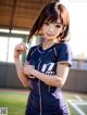 A woman in a baseball uniform holding a baseball.