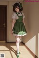 A girl in a green dress is standing in a hallway.