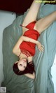 A woman in a red dress laying on a bed.