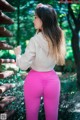 A woman in a white sweatshirt and pink leggings standing on a wooden bench.