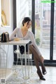 A woman sitting at a table in front of a window.