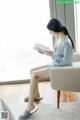 A woman sitting on a couch reading a book.