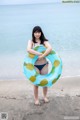 A woman in a bikini holding an inflatable ring on the beach.