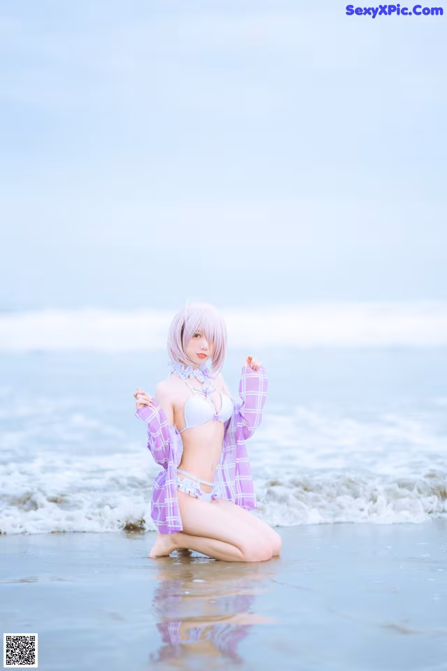 A woman in a bikini sitting on the beach.