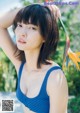 A woman in a blue bikini holding a flower.