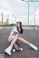 A woman sitting on a skateboard in the middle of a street.